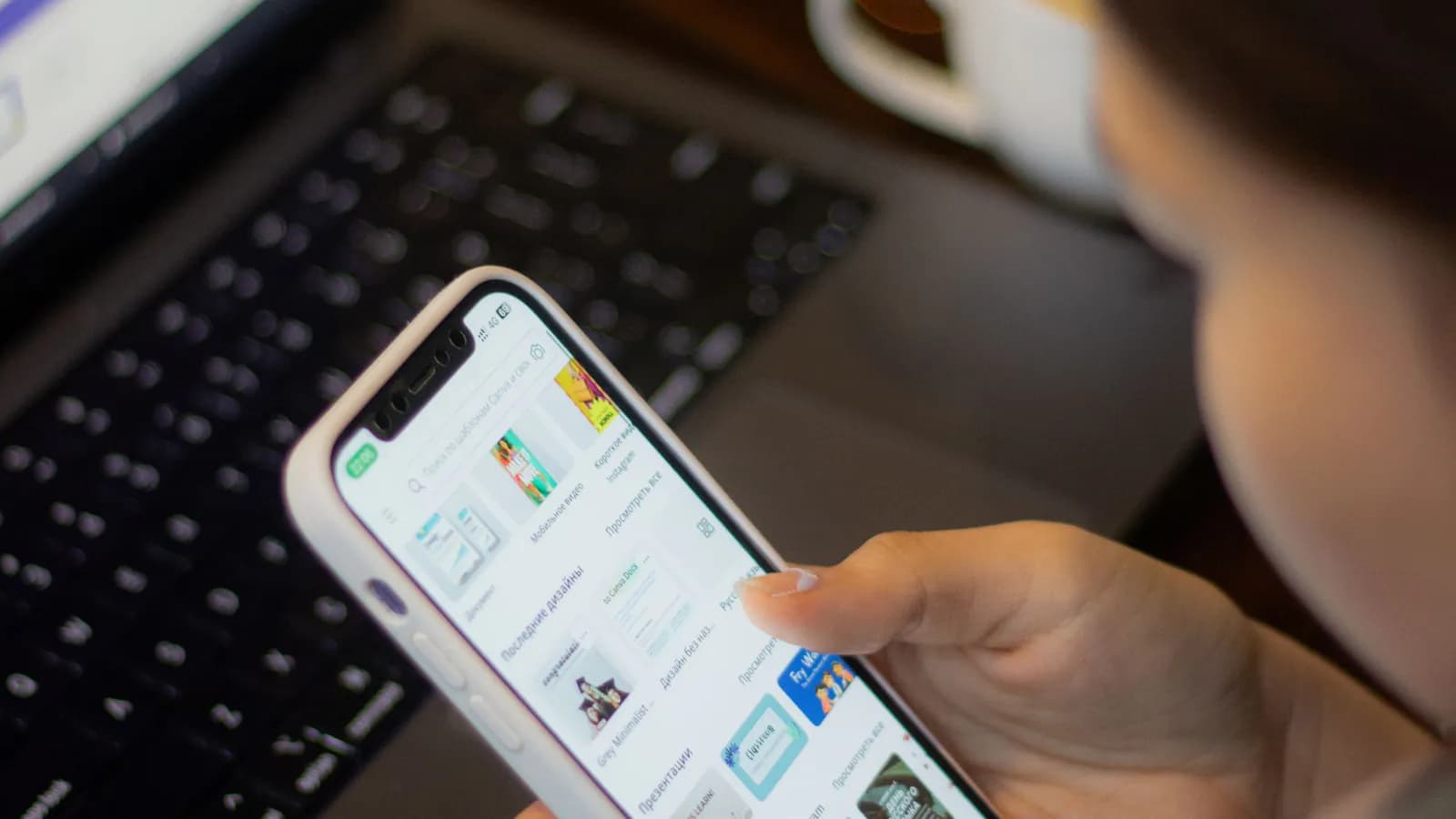 Seseorang membandingkan informasi digital melalui ponsel dan laptop